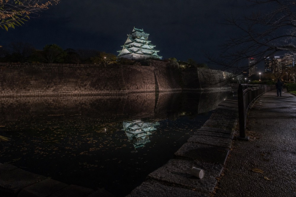 Floodlit Osaka Castle keep reflected in the inner moat after dark