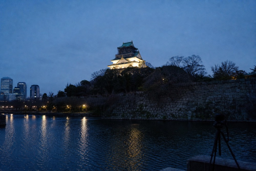 Floodlit Osaka Castle tower seen from across the water after dark