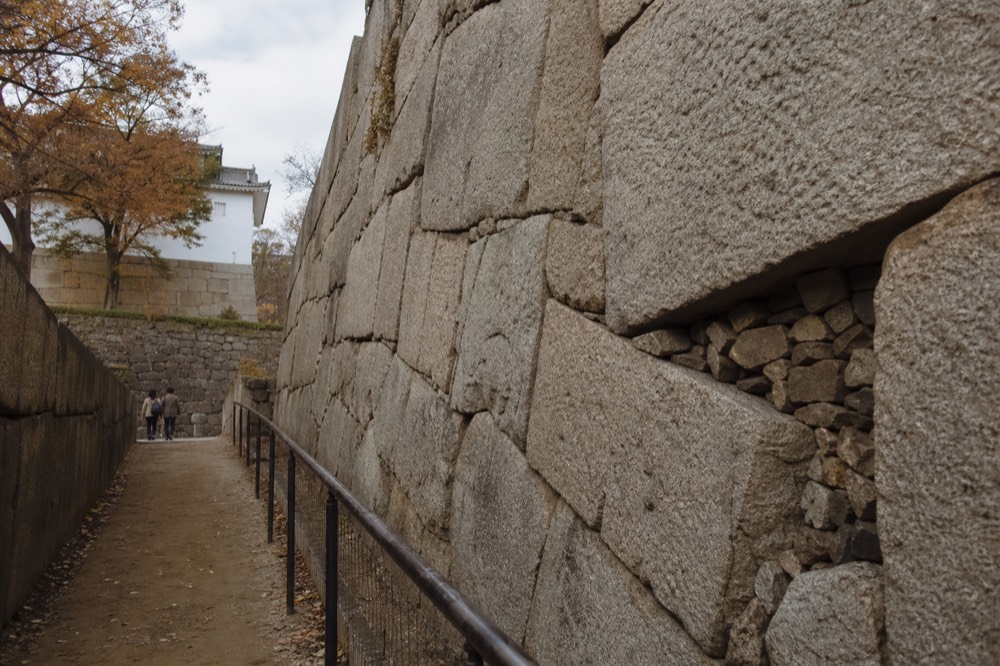 Massive grey stone wall of Osaka Castle below the tower