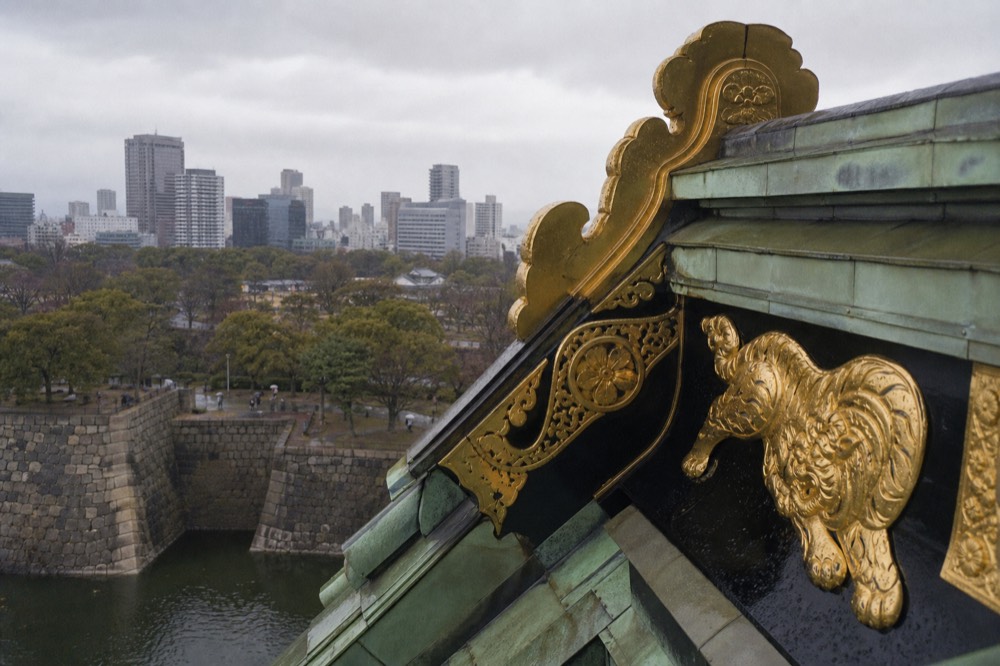 The golden tiger relief on the roof of Osaka Castle, with the green copper roof and the sky behind it
