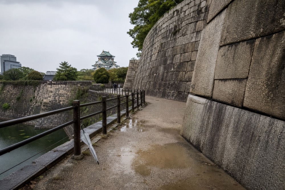 A stone wall built of large irregular blocks curves along the edge of a castle moat