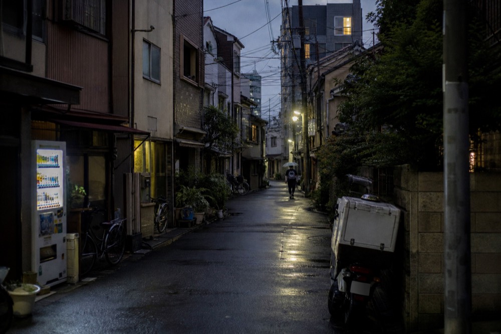 A narrow Osaka street with tightly packed buildings and overhead signage