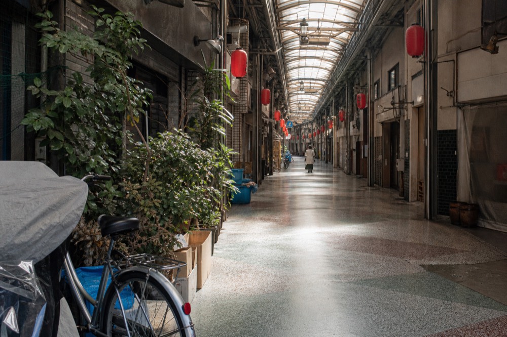 A covered shopping arcade in Osaka with shuttered shops and lanterns