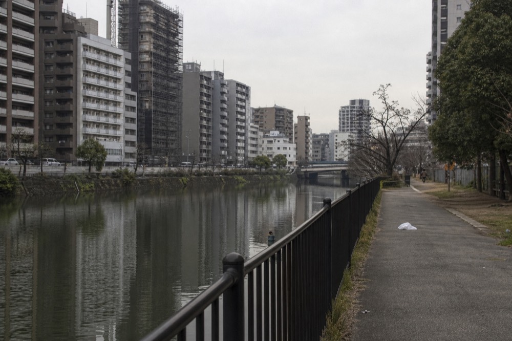 Modern Osaka apartment towers beside a river under an overcast sky