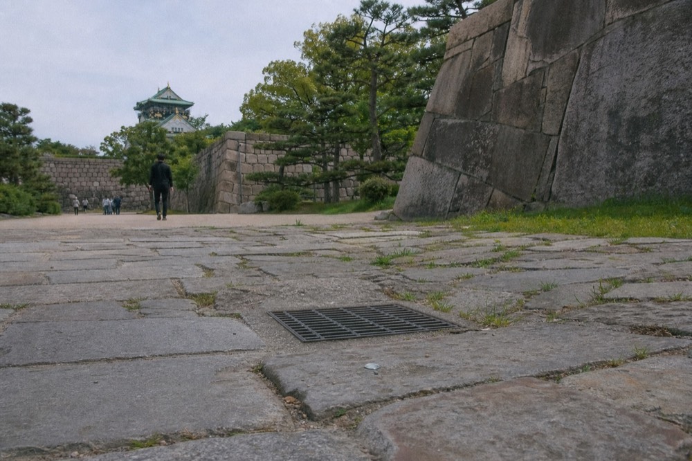 A quiet stone-paved plaza inside the castle grounds surrounded by old walls
