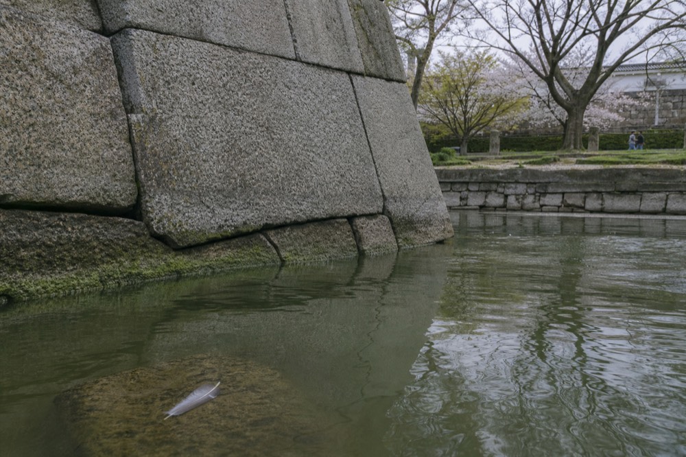 Stone wall of Osaka Castle with large fitted blocks above a water moat
