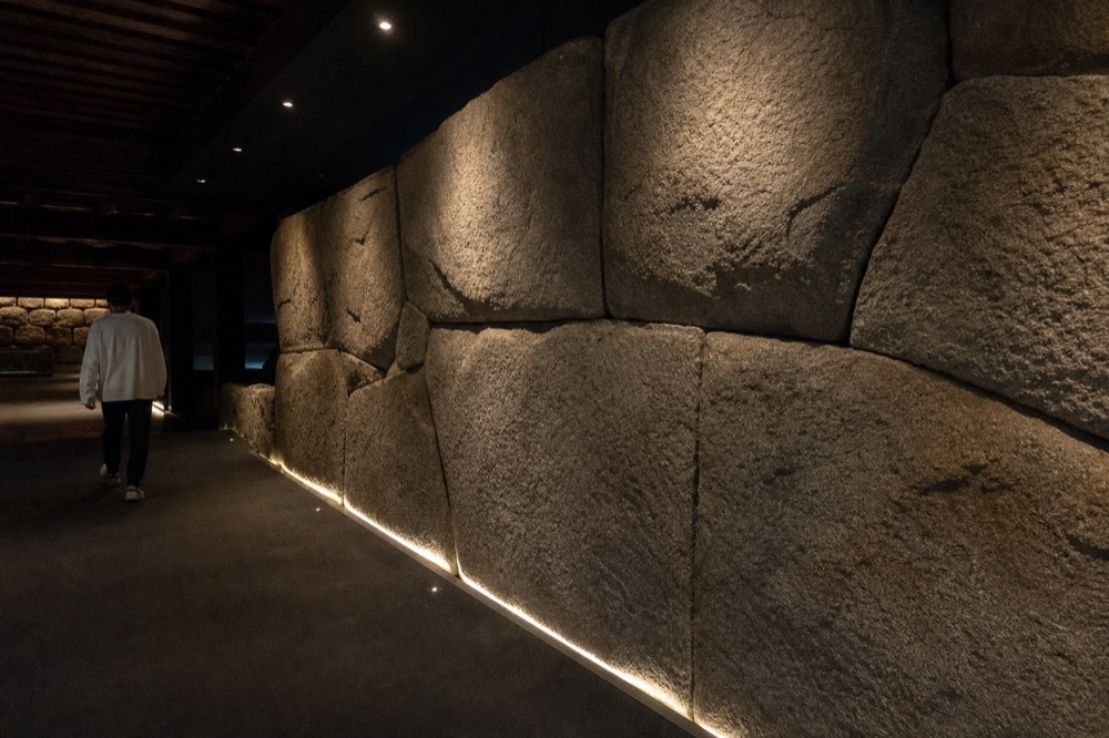 Interior of the Osaka Castle Toyotomi Stone Wall Museum with an ancient stone wall lit along the gallery