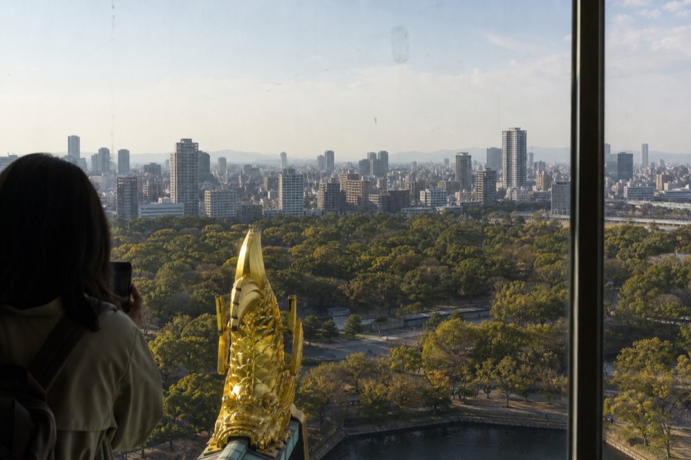 Panoramic view from the Osaka Castle 8F observation deck over the city skyline and green park