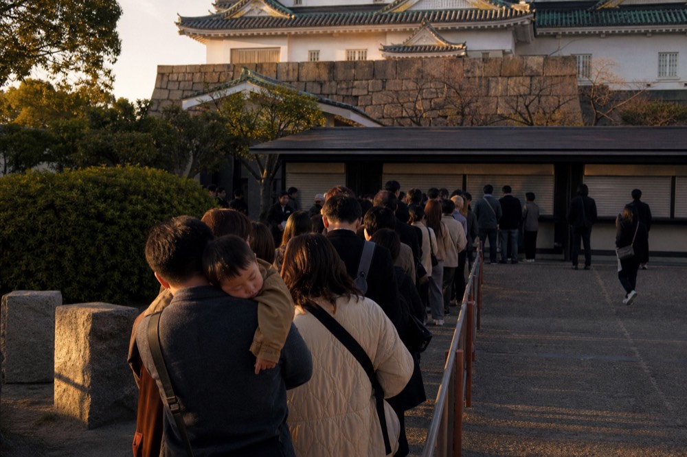Long queue of visitors waiting at the Osaka Castle ticket gate in warm afternoon light