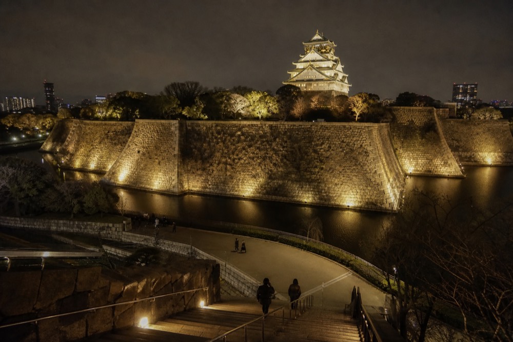 A wide panoramic view of the entire honmaru lit up at night, with the tower, walls, and moat all visible