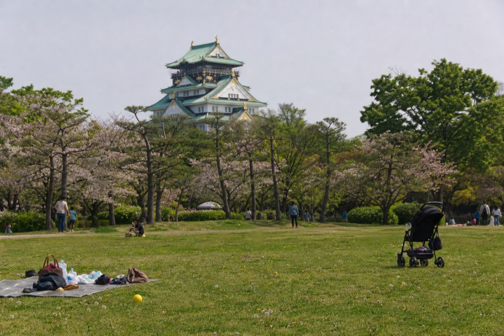 Osaka Castle tower behind the trees of the park lawn