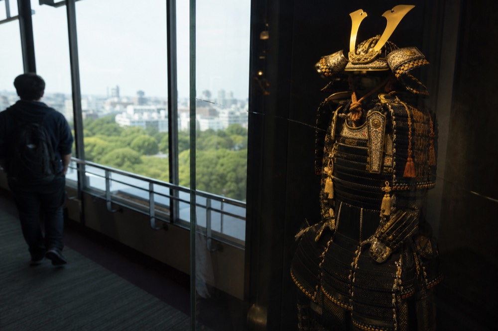 A suit of Japanese samurai armour with ornate helmet displayed in a glass museum case