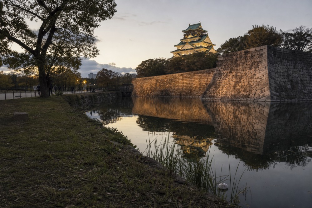 Late afternoon view of Osaka Castle from across the inner moat with soft golden light on the stone walls