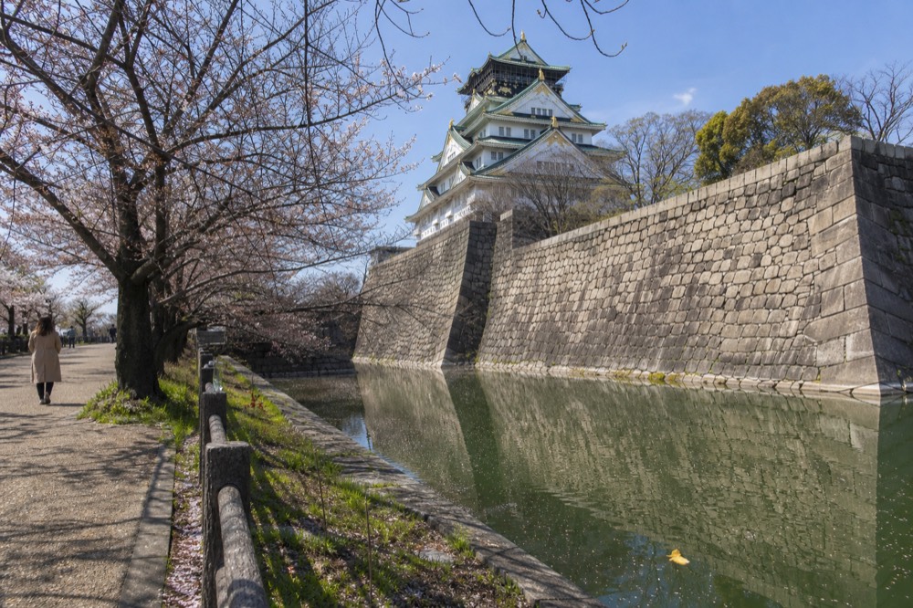 The inner moat and stone walls with the tower in the background on a sunny day