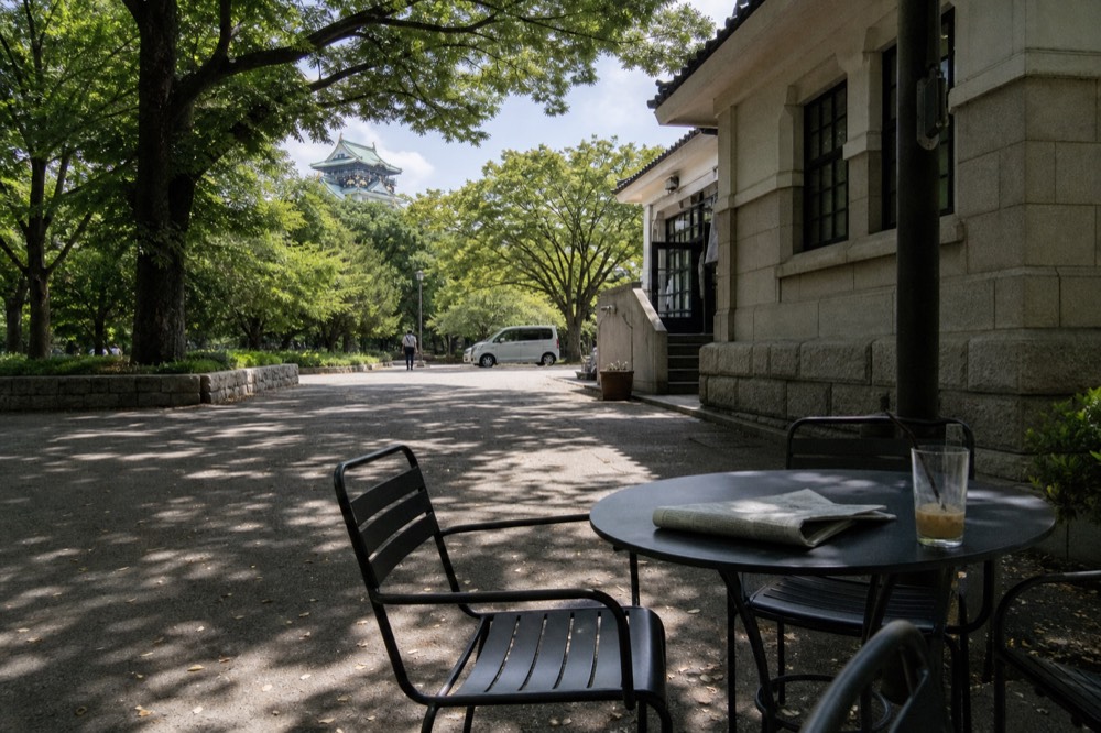 Historic stone building courtyard with outdoor cafe tables and shaded seating
