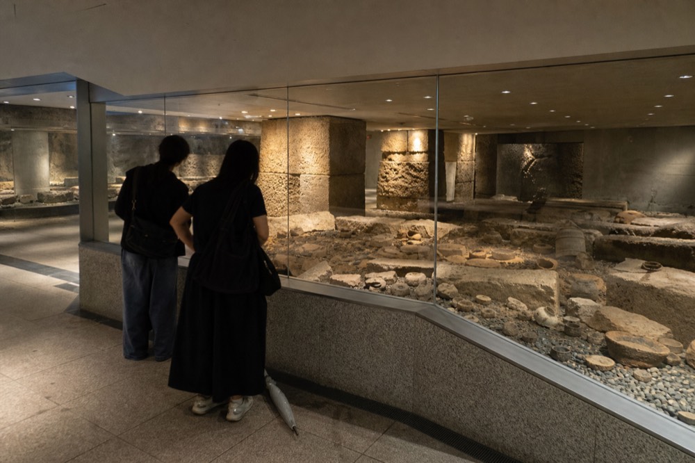 Visitors viewing a display of excavated artefacts behind glass in a museum gallery
